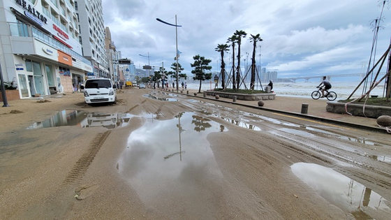 제11호 태풍 힌남노가 지나간 오늘(6일) 오전 부산 광안리해수욕장 해안도로가 폭풍해일에 밀려온 모래로 뒤덮여 차량이 통제되는 모습. 〈사진-연합뉴스〉  