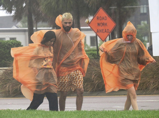 현지시간 28일 강한 비바람에 우비를 입고 이동하는 플로리다 주민들. 〈사진-AP·연합뉴스〉