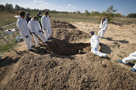 현지시간 7일 법의학자들이 우크라이나 리만 매장지에서 발굴 작업을 하는 모습. 〈사진-EPA·연합뉴스〉