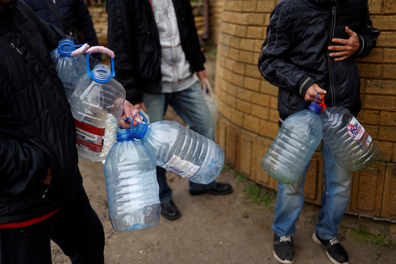 현지시간 21일 우크라이나 헤르손 주민들이 드니프로 강 근처에서 물을 채우기 위해 빈 통을 들고 기다리고 있다. 〈사진=로이터 연합뉴스〉