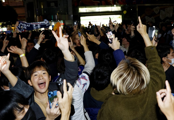 일본의 16강 진출 소식에 일본 도쿄 시민들이 환호하는 모습. 〈사진-로이터·연합뉴스〉