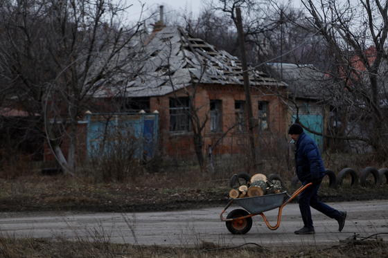 지난 26일 우크라이나 바흐무트에서 한 남성이 장작을 실은 손수레를 끌고 있다. 〈사진=연합뉴스〉