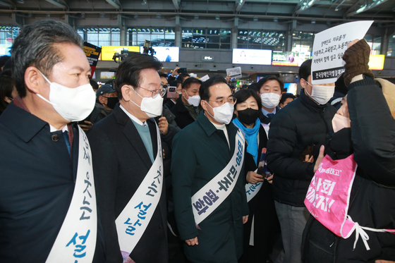 더불어민주당 이재명 대표가 설 연휴를 하루 앞둔 20일 오전 서울 용산역에서 설 귀성 인사를 하던 도중 피켓을 든 전국장애인차별철폐연대 관계자로부터 요구안을 듣고 있다. 〈사진=공동취재단〉