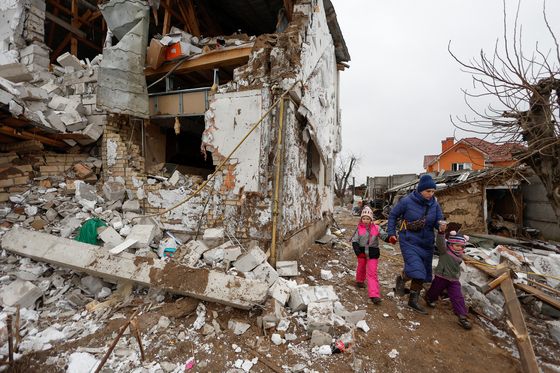 현지시간 26일 우크라이나 키이우 외곽 한 마을에서 한 시민이 러시아군의 공습으로 무너진 주택 옆을 걷고 있다. 〈사진=로이터〉