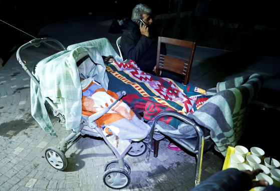 현지시간 20일 튀르키예 하타이주 안타키아에서 지진이 발생한 가운데 한 남성이 잠든 아이들 옆에서 전화하고 있다. 〈사진=로이터〉