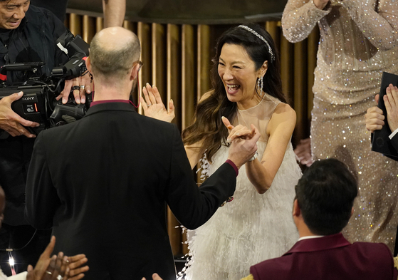 Michelle Yeoh, center, reacts with excitement as Daniel Scheinert, left, and Daniel Kwan accept the award for best director for ″Everything Everywhere All at Once″ at the Oscars on Sunday, March 12, 2023, at the Dolby Theatre in Los Angeles. (AP Photo/Chris Pizzello)