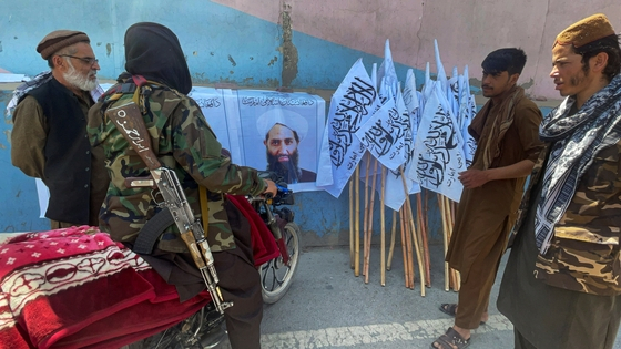 탈레반 대원들이 2021년 8월 아프가니스탄 카불에서 최고지도자인 하이바툴라 아쿤드자다의 사진을 보고 있다. 〈사진=로이터〉