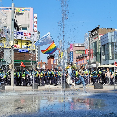 대구퀴어문화축제가 열리는 오늘(17일) 오전 경찰과 행정 당국이 충돌하는 가운데 행사 참가자가 무지개 깃발을 들고 걸어가고 있다. 〈사진=연합뉴스〉