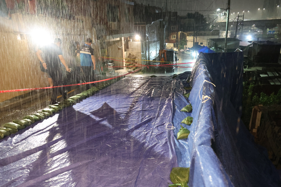 13일 폭우로 축대가 무너진 서울 서대문구 홍제천로 도로에 추가 붕괴를 막기 위한 방수포가 설치돼 있다. 〈사진=연합뉴스〉