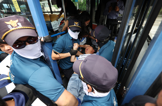 전장연 활동가가 버스 탑승을 시도하는 과정에서 경찰에 끌려나오는 모습. 〈사진=연합뉴스〉