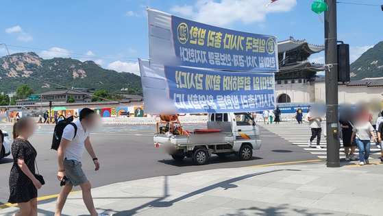 정당 현수막 끈을 피해 고개를 숙이고 걷는 보행자들. 〈사진=이지현 기자〉