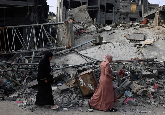 28일(현지시간) 가자지구 남부 라파에서 이스라엘의 폭격 여파로 파괴된 건물 앞을 사람들이 지나가고 있다. 〈사진=AFP/연합뉴스〉