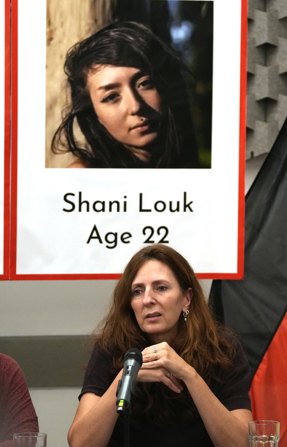 지난 17일 샤니 룩의 모친 리카르다 룩이 텔아비브에서 샤니의 플래카드 아래 앉아 있다. 〈사진=AP·연합뉴스〉