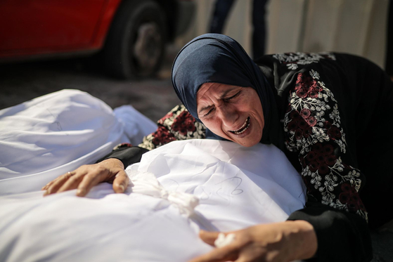 팔레스타인 여성이 숨진 유가족의 시신을 붙잡고 절규하고 있다 〈사진=Anadolu Agency〉