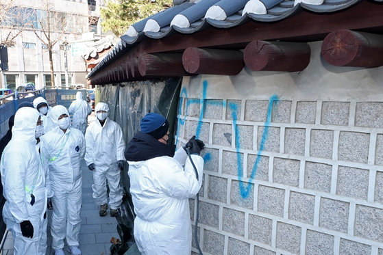 어제(17일) 오전 서울 종로구 국립고궁박물관 쪽문 경복궁 담벼락 앞에서 궁능유적본부 관계자들이 전날 누군가가 스프레이로 쓴 낙서를 제거하고 있다. 〈사진=공동취재단〉