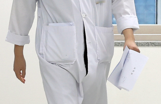 19일 오전 광주 동구 전남대학교병원 교육수련실 앞에서 한 전공의가 사직서를 들고 가고 있다. 〈사진=연합뉴스〉