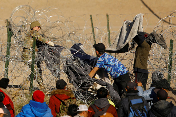 미국 텍사스주 방위군이 멕시코 국경을 경비하고 있는 가운데 이민자들이 철조망을 넘어가려고 시도하는 모습