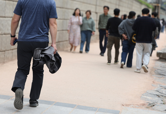 서울 청계천에서 시민이 겉옷을 들고 산책을 하고 있다. 〈자료사진=연합뉴스〉