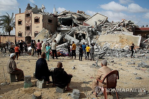 이스라엘의 공습으로 무너진 건물 더미를 지켜보는 가자지구 주민들 〈사진=로이터 연합뉴스〉
