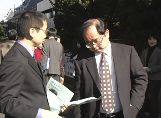 2004년 12월, 도쿄지방재판소 앞에서 시민들에게 강제동원 피해 사실을 적은 유인물을 건네고 있는 야노 히데키 국장(왼쪽). 〈사진=민족문제연구소〉