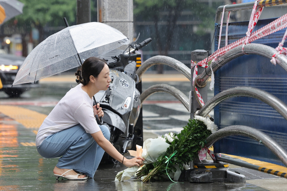 폭우가 쏟아지는 날씨에도 시민들의 추모 발길이 이어졌다. 사진은 시청역 사고 현장에 마련된 추모 공간에서 한 시민이 눈물을 참으며 국화꽃을 놓고 있는 모습. 〈사진=연합뉴스〉