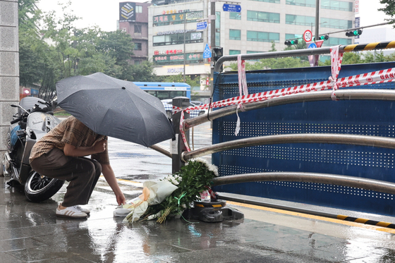 시청역 사고 현장을 찾은 시민이 국화꽃을 놓는 모습. 〈사진=연합뉴스〉