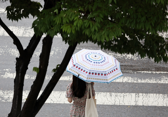 지난 5일 광주 서구 치평동에서 한 시민이 내리는 소나기에 우산을 쓰고 걷고 있다. 〈사진=연합뉴스〉