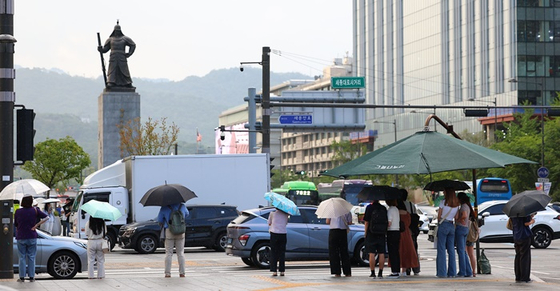 지난 19일 오후 서울 세종로사거리 시민들이 우산을 쓴 채 횡단보도 신호를 기다리고 있다. 〈사진=연합뉴스〉