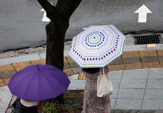 지난달 5일 광주 서구 치평동에서 한 시민이 내리는 소나기에 우산을 쓰고 걷고 있다. 〈사진=연합뉴스〉