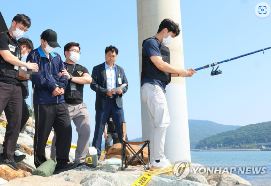 지난해 7월 인천시 중구 덕교동 잠진도 제방에서 해경이 바다에 아내를 빠트리고 돌 던져 살해한 혐의를 받는 30대 남편 A씨에 대해 현장 검증을 진행하고 있다. 〈사진=연합뉴스〉 